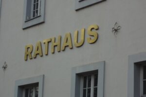 Goldfarbener Schriftzug "Rathaus" auf der Fassade des Trierer Rathauses.